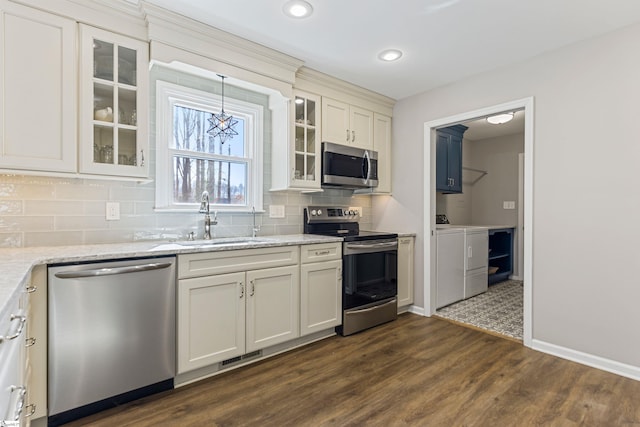 kitchen featuring sink, dark hardwood / wood-style flooring, stainless steel appliances, washer and clothes dryer, and backsplash