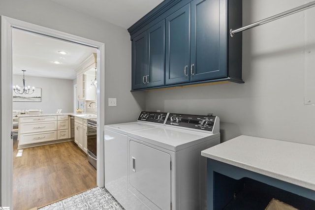 washroom with washer and dryer, sink, cabinets, a notable chandelier, and light hardwood / wood-style floors