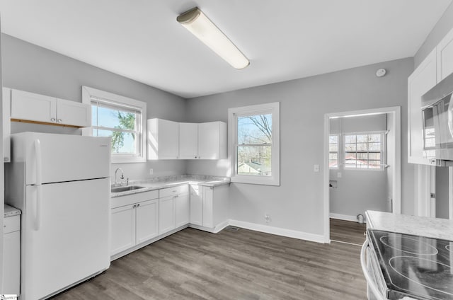 kitchen with plenty of natural light, sink, white fridge, and white cabinets