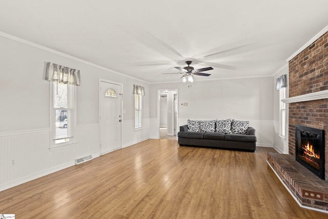 unfurnished living room featuring crown molding, a brick fireplace, and light wood-type flooring