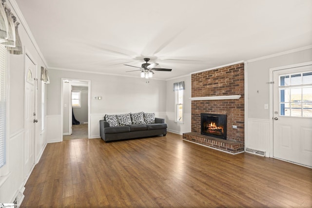 unfurnished living room featuring dark hardwood / wood-style flooring, a fireplace, ornamental molding, and ceiling fan