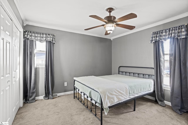 carpeted bedroom featuring ornamental molding, ceiling fan, and a closet