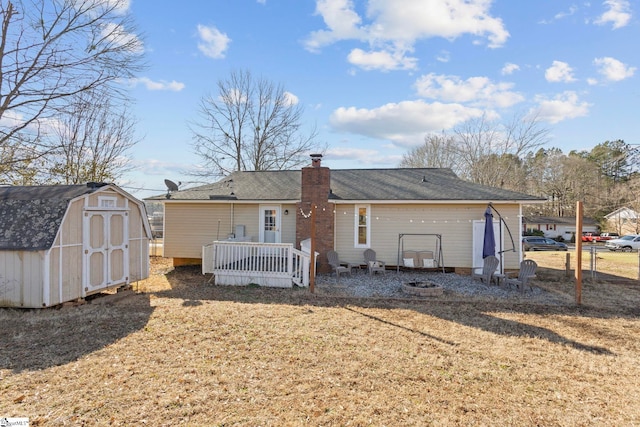 rear view of house featuring a lawn and a shed