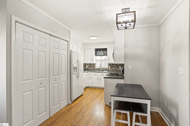 kitchen featuring backsplash, white refrigerator with ice dispenser, light wood-type flooring, and white cabinets