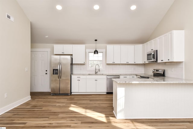 kitchen featuring pendant lighting, stainless steel appliances, kitchen peninsula, and white cabinets