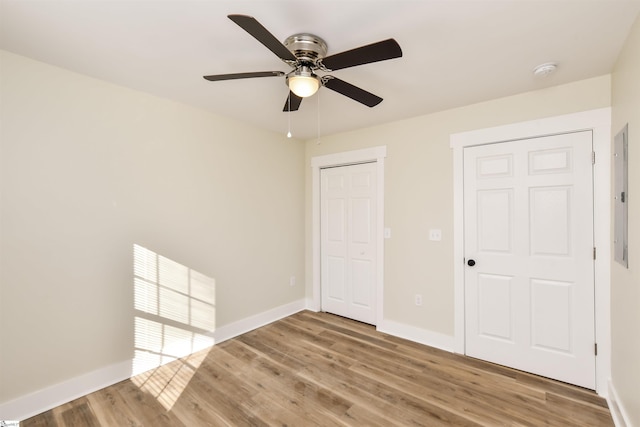 unfurnished bedroom with hardwood / wood-style flooring, ceiling fan, electric panel, and a closet