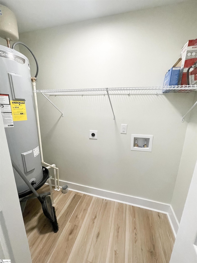 washroom with water heater, hardwood / wood-style floors, hookup for a washing machine, and hookup for an electric dryer