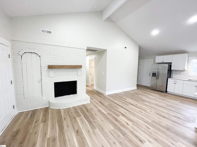 unfurnished living room with beamed ceiling, a fireplace, high vaulted ceiling, and light hardwood / wood-style flooring