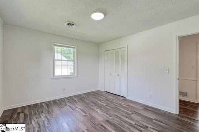 unfurnished bedroom featuring hardwood / wood-style flooring, a closet, and a textured ceiling