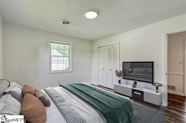 bedroom featuring a textured ceiling, dark hardwood / wood-style flooring, and a closet