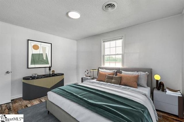 bedroom with dark hardwood / wood-style flooring and a textured ceiling