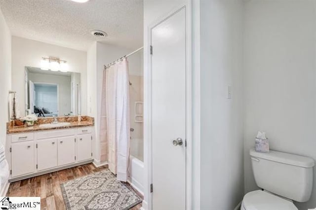 full bathroom with toilet, shower / tub combo, a textured ceiling, vanity, and hardwood / wood-style floors