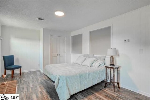 bedroom with a closet, dark hardwood / wood-style floors, and a textured ceiling