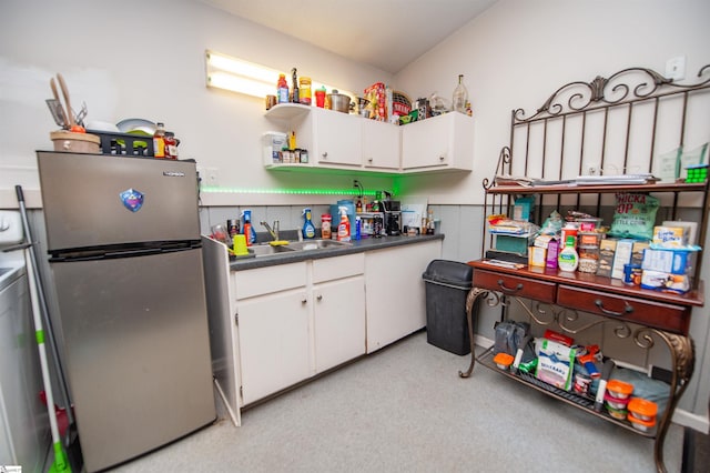 kitchen with white cabinetry, sink, and stainless steel refrigerator