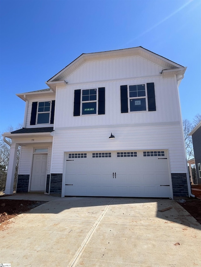 view of front of property featuring concrete driveway, an attached garage, and stone siding