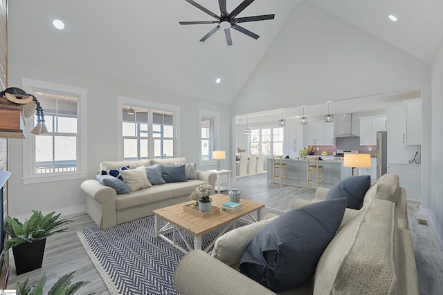 living room featuring ceiling fan, high vaulted ceiling, a wealth of natural light, and light wood-type flooring