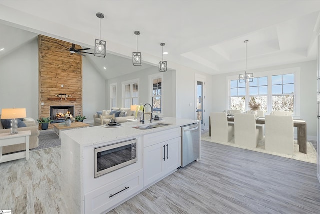 kitchen featuring pendant lighting, appliances with stainless steel finishes, an island with sink, and white cabinets