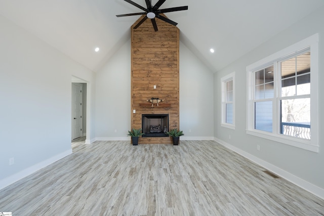 unfurnished living room featuring ceiling fan, a stone fireplace, high vaulted ceiling, and light hardwood / wood-style flooring