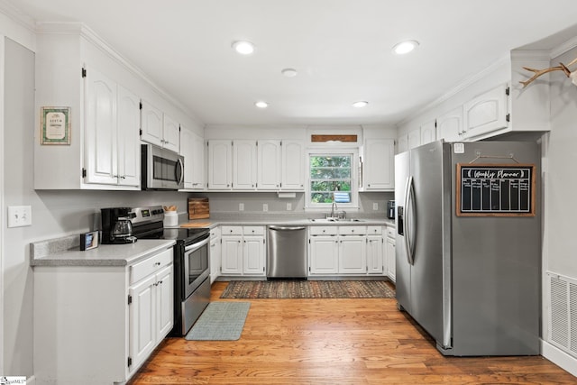 kitchen featuring sink, hardwood / wood-style floors, white cabinets, and appliances with stainless steel finishes