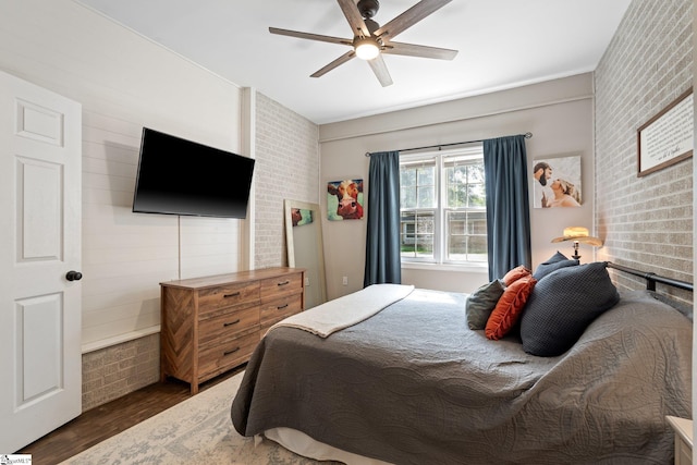 bedroom with brick wall, dark wood-type flooring, and ceiling fan