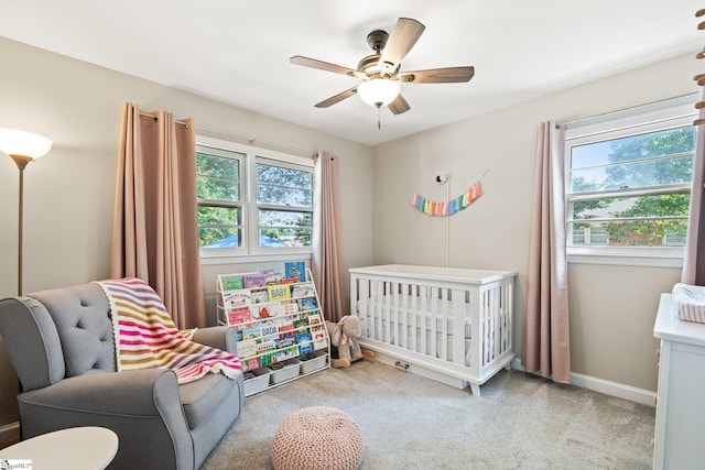 bedroom featuring light carpet, a crib, and ceiling fan