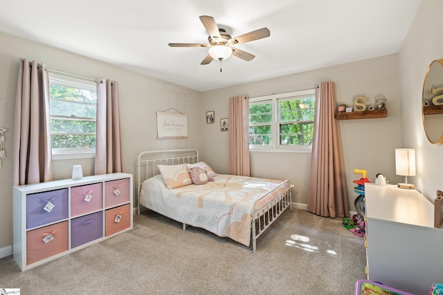 bedroom featuring multiple windows, light colored carpet, and ceiling fan