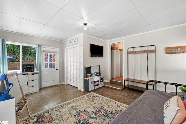 living room with crown molding, dark wood-type flooring, and a paneled ceiling