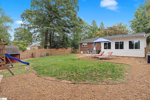 rear view of house with central AC unit, a yard, a patio, and a playground