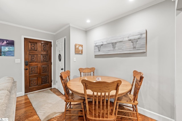 dining space with crown molding and wood-type flooring