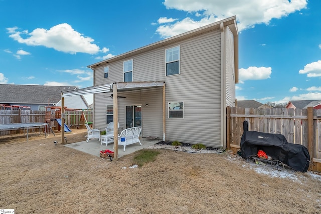 back of house featuring a trampoline, a lawn, a patio, and a playground