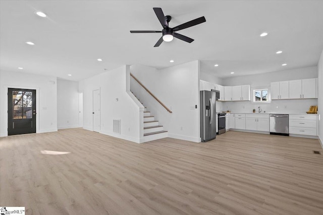 unfurnished living room with sink, light hardwood / wood-style floors, and ceiling fan