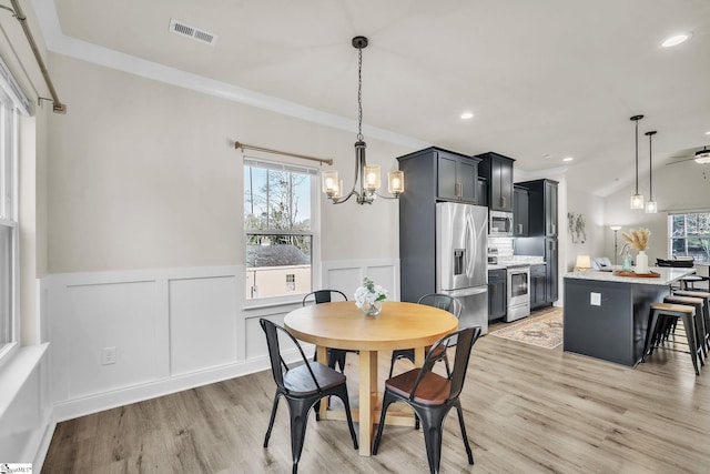 dining space with ornamental molding, light hardwood / wood-style floors, and a chandelier