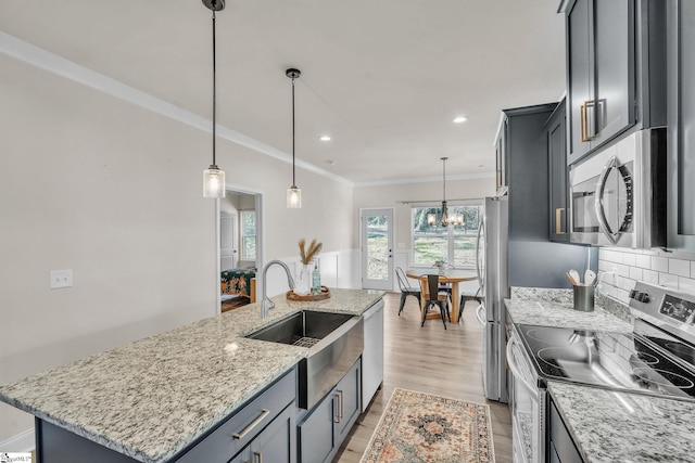 kitchen with pendant lighting, sink, decorative backsplash, a kitchen island with sink, and stainless steel appliances