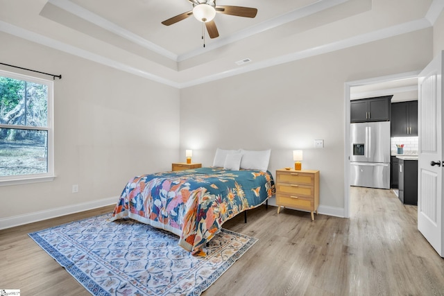 bedroom featuring crown molding, light hardwood / wood-style flooring, ceiling fan, a tray ceiling, and stainless steel fridge with ice dispenser