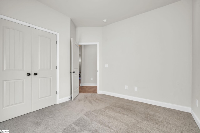 unfurnished bedroom featuring light colored carpet and a closet