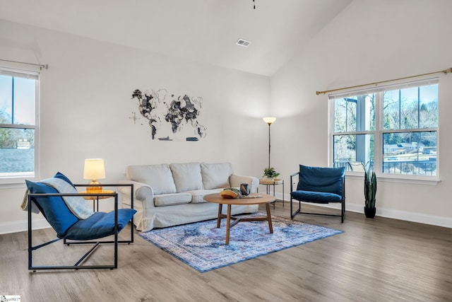 living room featuring hardwood / wood-style flooring, vaulted ceiling, and a healthy amount of sunlight