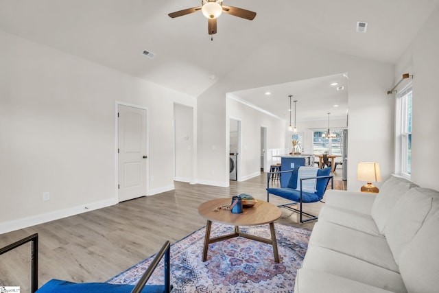 living room with high vaulted ceiling, wood-type flooring, washer / clothes dryer, and ceiling fan with notable chandelier