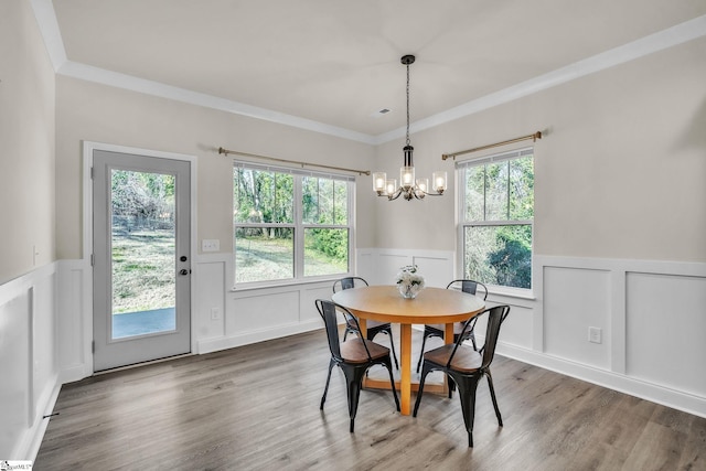 dining area featuring an inviting chandelier, ornamental molding, and wood-type flooring