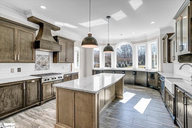 kitchen with hanging light fixtures, light stone counters, stainless steel gas cooktop, a kitchen island, and custom exhaust hood