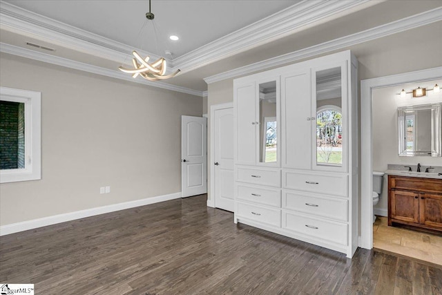 unfurnished bedroom with crown molding, ensuite bath, dark hardwood / wood-style flooring, and a chandelier