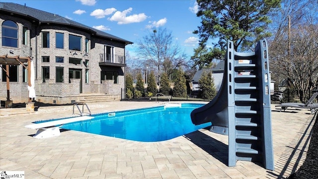 view of swimming pool featuring a pergola, a water slide, a diving board, and a patio area