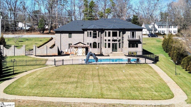 back of property with a balcony, a fenced in pool, and a lawn