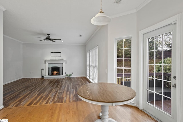 unfurnished living room featuring a fireplace, wood-type flooring, ornamental molding, and plenty of natural light