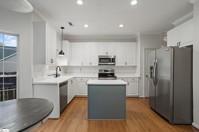 kitchen featuring sink, appliances with stainless steel finishes, white cabinetry, hanging light fixtures, and a kitchen island