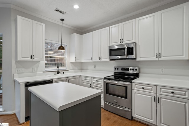 kitchen with pendant lighting, sink, white cabinets, a center island, and stainless steel appliances