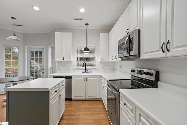 kitchen featuring pendant lighting, sink, crown molding, appliances with stainless steel finishes, and white cabinets