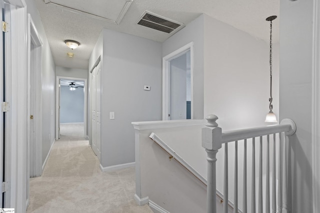 corridor featuring light colored carpet and a textured ceiling