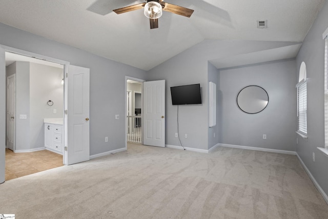 unfurnished bedroom featuring vaulted ceiling, light colored carpet, ceiling fan, and ensuite bathroom