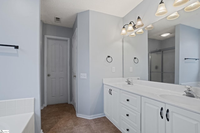 bathroom with vanity, shower with separate bathtub, and a textured ceiling