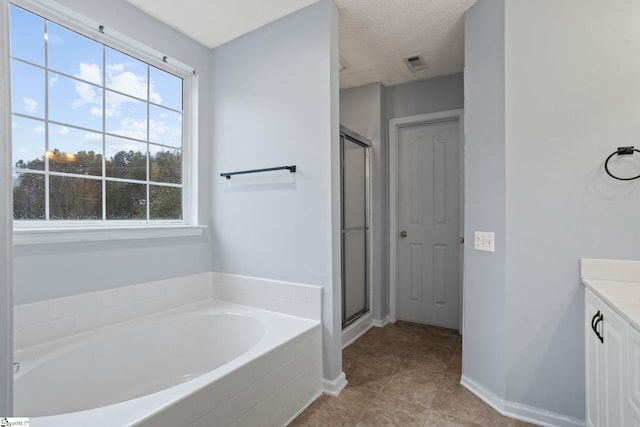 bathroom featuring a textured ceiling, plenty of natural light, and separate shower and tub